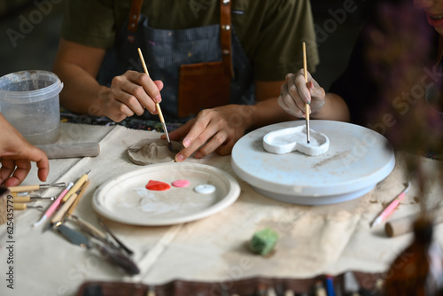 Image of young asian man enjoying creative process, creating handmade ceramics in pottery workshop