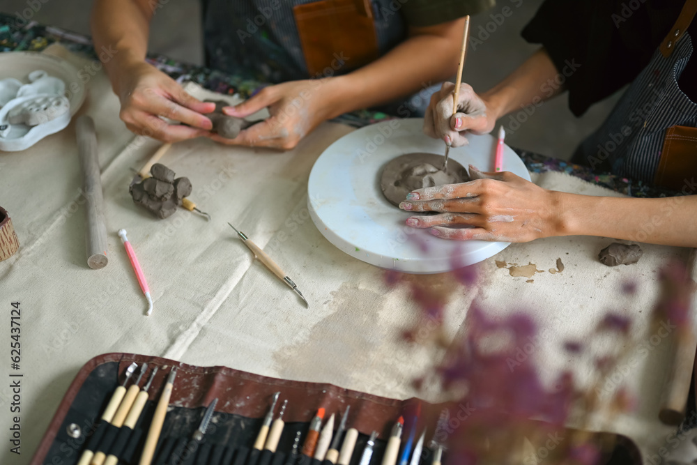 Obraz premium Craftspeople wearing aprons working with raw clay, shaping and decorating pottery in workshop