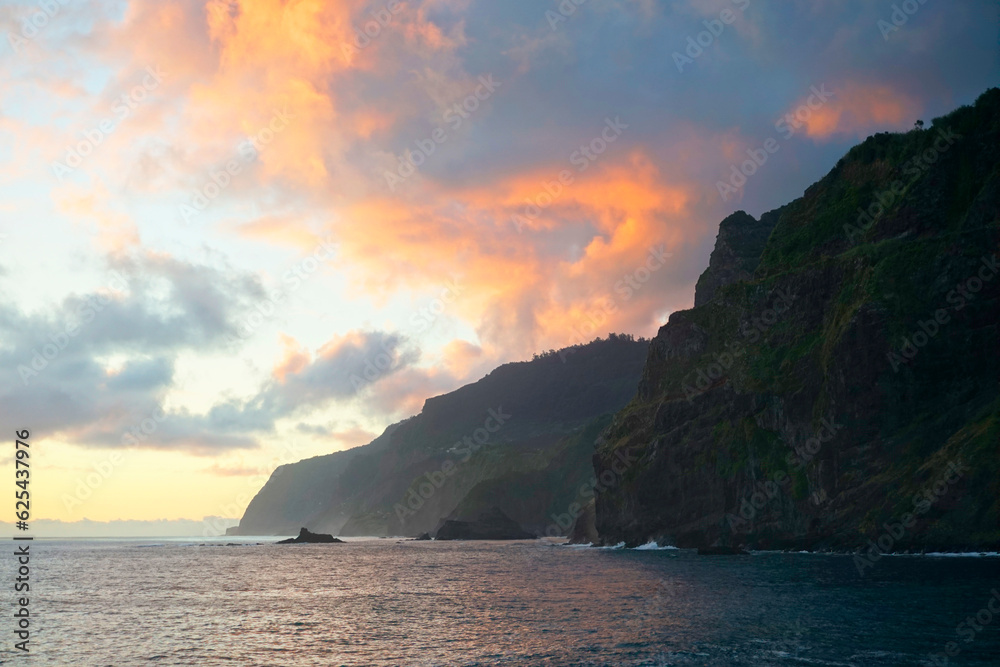 Ocean surface in the morning on Madeira island. Coastal rocks. And pink clouds in the rays of the rising sun.
Glare and reflection on the waves. horizontal shot


  