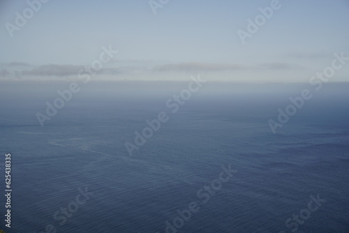 View from a cliff in Madeira to the Atlantic Ocean. Gray haze in the early morning. Disappearing horizon.