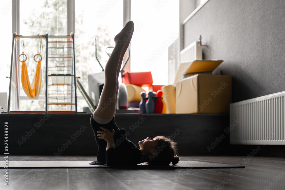 Small child girl doing candlestick exercise during her dance, gymnastic