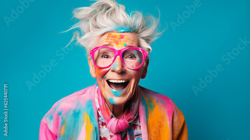 Elegant elderly female artist in a colorful smock with paint brushes on blue background