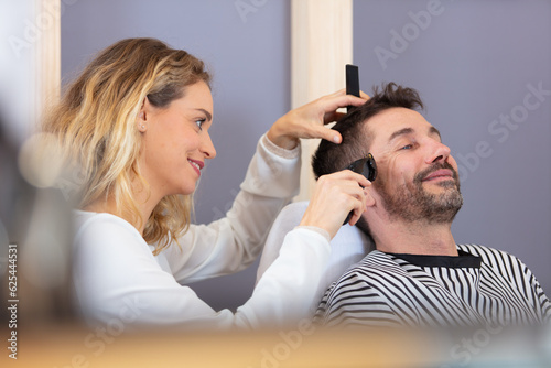 hairdresser using clippers on a contented male customer photo