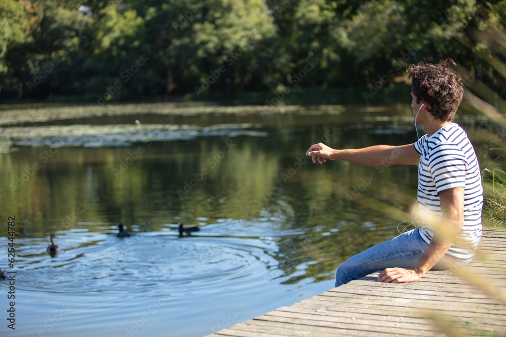 Fototapeta premium young man feeding ducks in a pond