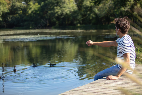 Fototapeta Naklejka Na Ścianę i Meble -  young man feeding ducks in a pond