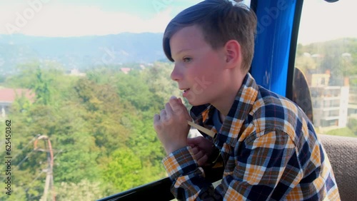 Interested teen boy tourist sitting in funicular cabin of cable car in Batumi Georgia. Teenager on vacations travelling in mountains admiring breathtaking views. Travel, tourism, journey, wanderlust. photo