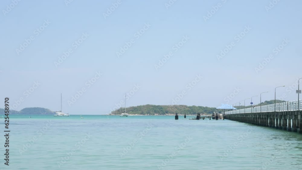 beach concrete pier over turquoise clear blue sea in Phuket island at Thailand under sunny sunshine day with green island and some yachts in sea, summer holiday vacation beach concrete pier over turquoise clear blue sea in Phuket island at Thailand under sunny sunshine day with green island and some yachts in sea, summer holiday vacation