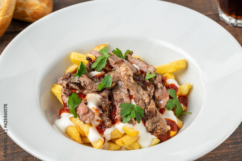 Turkish food Çökertme Kebab. Kebab made with thinly sliced beef steak on french fries and yoghurt Turkish food Çökertme Kebab. Kebab made with thinly sliced beef steak on french fries and yoghurt