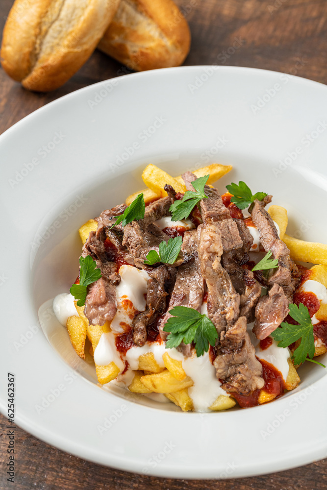 Turkish food Çökertme Kebab. Kebab made with thinly sliced beef steak on french fries and yoghurt Turkish food Çökertme Kebab. Kebab made with thinly sliced beef steak on french fries and yoghurt