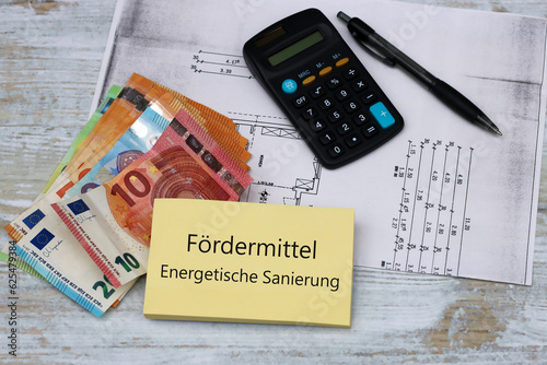 Fördermittel energetische Sanierung: Taschenrechner,  Geldscheine und der Text Fördermittel energetische Sanierung auf einem Notizblock. photo