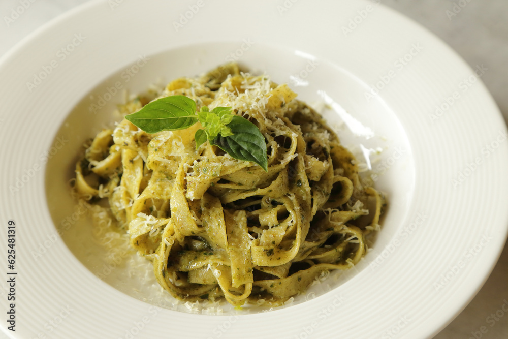 Green pesto pasta with basil. Fettuccine pesto sauce recipe. Colorful healthy food in a bowl.