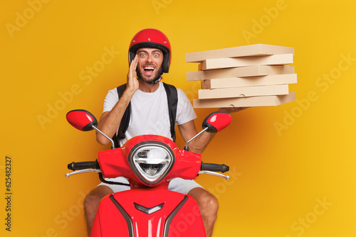 Pizza guy delivers orders to clients on red scooter, dressed in red helmet and white t-shirt holding some pizza boxes in one hand, fast drive concept, copy space