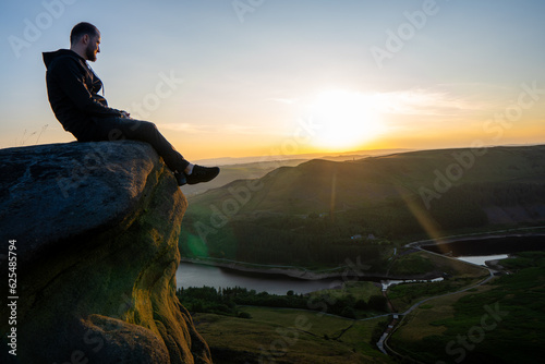 Man sat at the top of the cliff enjoying the sunset