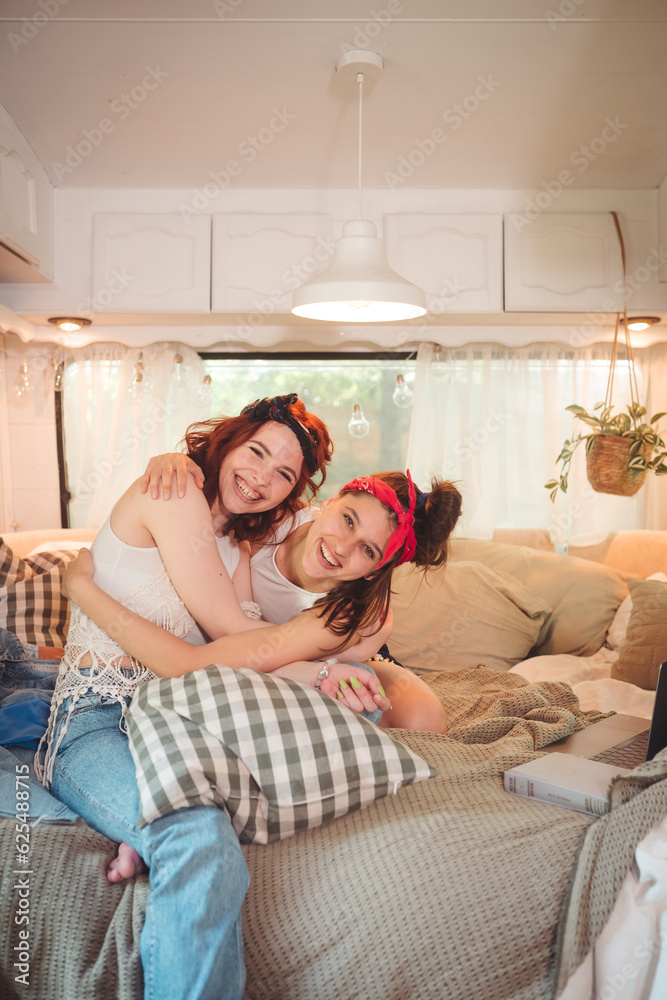 Portrait of a cute lesbian couple. Two girls spend time tenderly together in a camper trailer. Love and attitude. LGBT concept Portrait of a cute lesbian couple. Two girls spend time tenderly together in a camper trailer. Love and attitude. LGBT concept
