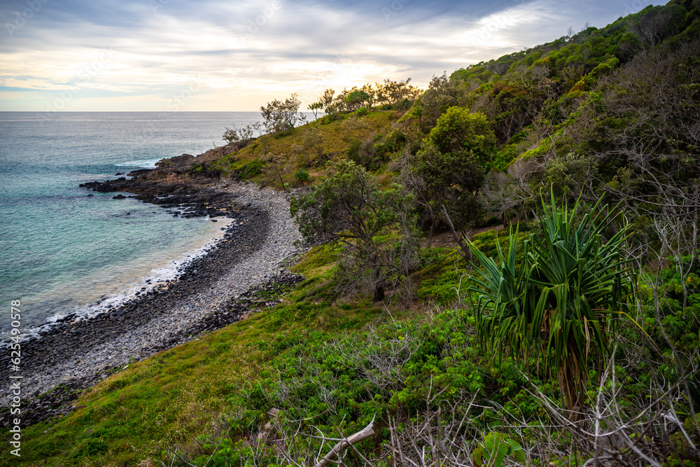 sunset over a beautiful cameral hidden little cove bay covered with greenery in Noosa National Park, Queensland, Australia	