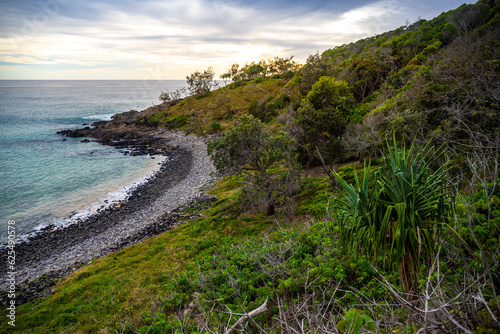 sunset over a beautiful cameral hidden little cove bay covered with greenery in Noosa National Park  Queensland  Australia 