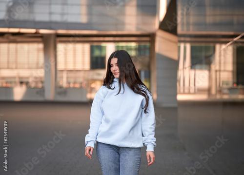 Brunette woman wearing a sweatshirt with a hood. Beautiful girl blank one color jumper.