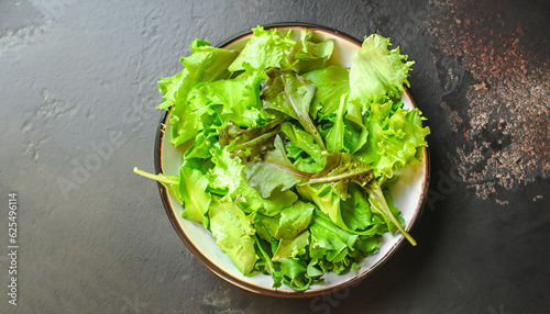 mix lettuce leaves salad in a plate  fresh green snack . food background. top