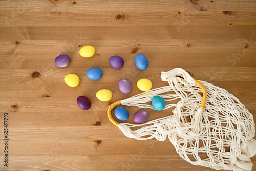 Easter eggs in a string bag on a wooden background, top view