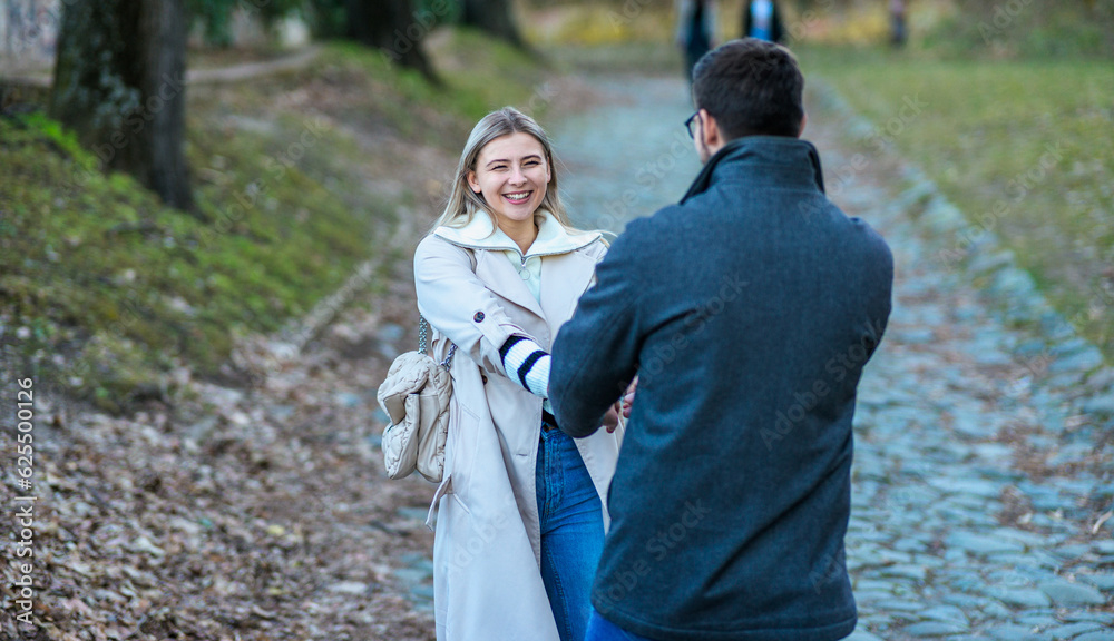 Obraz premium Portrait of a couple walking in the park holding hands while laughing.