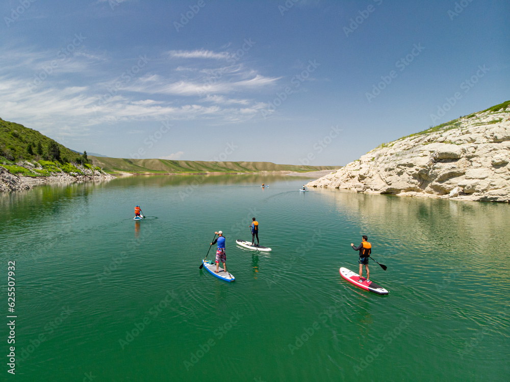 A group of tourists swims on SUP boards on a mountain lake