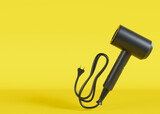Hair dryer on yellow background with copy space. Empty space for text, advertising. Professional hair style tool. Realistic hairdryer for hairdresser salon or home usage. Tool for drying hair. 3D.