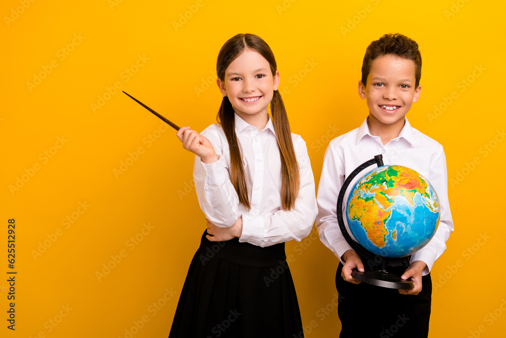 Fototapeta premium Photo of sweet positive preteen schoolchildren wear white shirts learning geography empty space isolated yellow color background