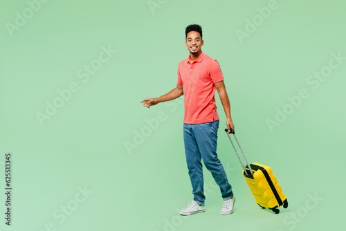 Sideways traveler man wears summer casual clothes hold bag suitcase walk go isolated on plain green background. Tourist travel abroad in free spare time rest getaway. Air flight trip journey concept. #625513345