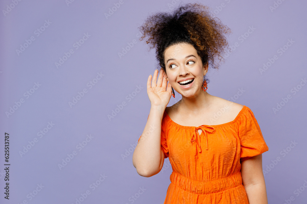 Young curious nosy latin woman she wears orange blouse casual clothes try to hear you overhear listening intently isolated on plain pastel light purple background studio portrait. Lifestyle concept. Young curious nosy latin woman she wears orange blouse casual clothes try to hear you overhear listening intently isolated on plain pastel light purple background studio portrait. Lifestyle concept.