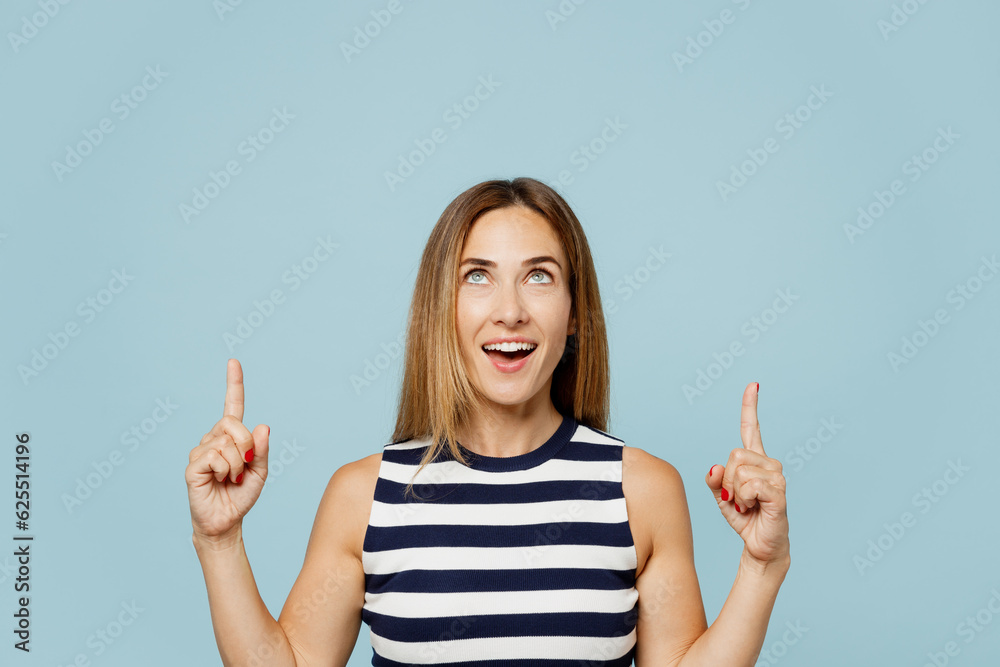 Young woman wears striped tank shirt casual clothes point index finger overhead indicate on workspace area copy space mock up isolated on plain pastel blue cyan background studio. Lifestyle concept. Young woman wears striped tank shirt casual clothes point index finger overhead indicate on workspace area copy space mock up isolated on plain pastel blue cyan background studio. Lifestyle concept.