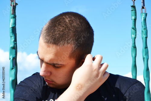 A young autistic guy holds his ear on a swing autistic behavior traits