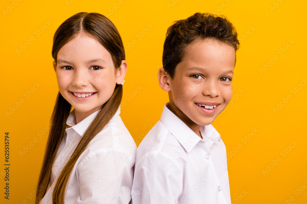 Photo of cheerful sweet preteen schoolchildren wear white shirts smiling isolated yellow color background