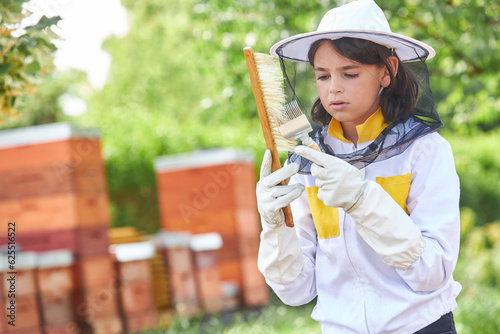 Girl analyzing hive fork and brush at apiary garden © Robert Kneschke