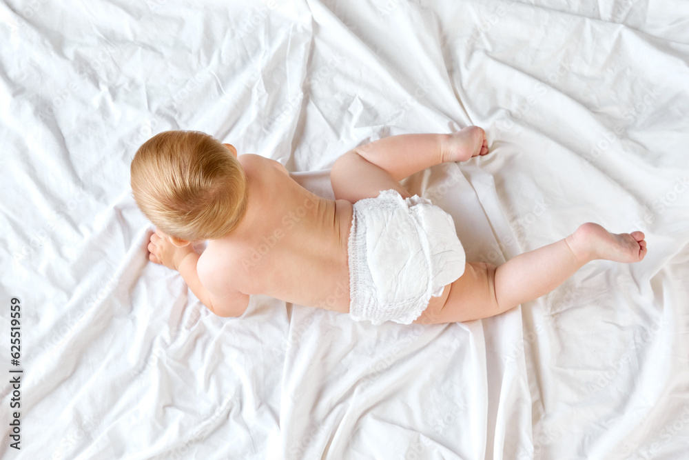 Beautiful, cute little baby, toddler in diaper calmly lying on bed, playing and resting. Taking care after child. Concept of childhood, newborn lifestyle, happiness, care. Copy space for ad Beautiful, cute little baby, toddler in diaper calmly lying on bed, playing and resting. Taking care after child. Concept of childhood, newborn lifestyle, happiness, care. Copy space for ad