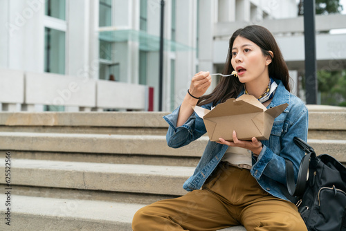 Korean international students girl enjoying food sitting on the outside stairs during lunch break in the Los Angeles