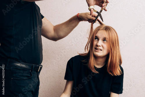 Girl cuts hair with scissors. Barbershop problem. trimmed.