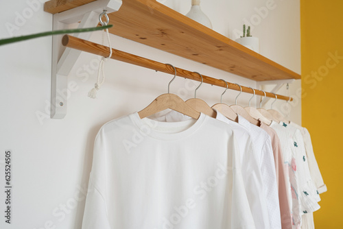 White t-shirt hanging on a wooden hanger in the interior © Lys Owl