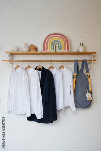 White shirts and a blue jacket hanging on a wooden shelf in the teen room