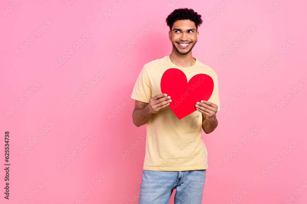 Photo young boyfriend guy look side flirty expression hold big red paper heart wear shirt jeans isolated pink color background