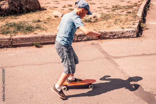 a boy rides a skateboard on an asphalt road on a sunny day