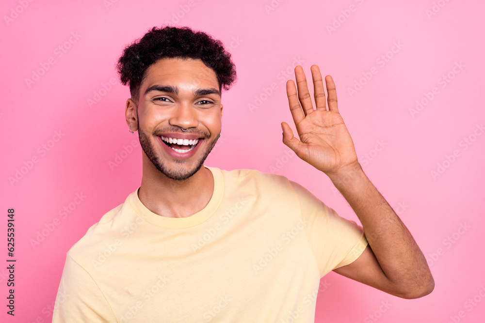 Photo of funny guy toothy smiling raise hand waving his friends say hi hello wear stylish yellow shirt isolated pink color background Photo of funny guy toothy smiling raise hand waving his friends say hi hello wear stylish yellow shirt isolated pink color background