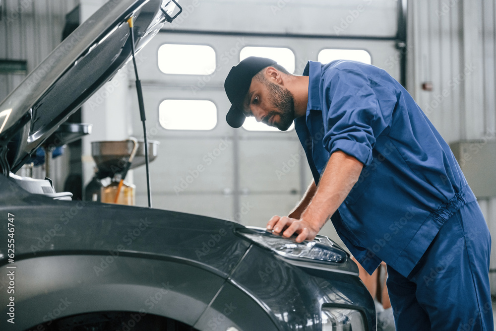 Hood is opened. Auto mechanic working in garage. Repair service Hood is opened. Auto mechanic working in garage. Repair service