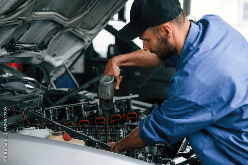 Adjusting the screws. Auto mechanic working in garage. Repair service Adjusting the screws. Auto mechanic working in garage. Repair service
