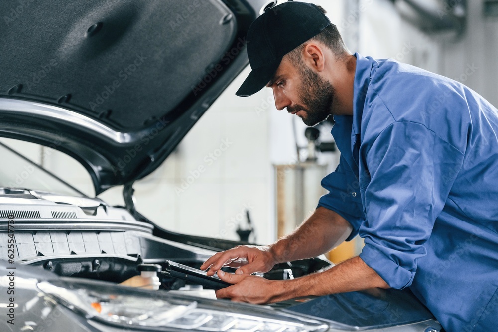 Using tablet. Auto mechanic working in garage. Repair service Using tablet. Auto mechanic working in garage. Repair service
