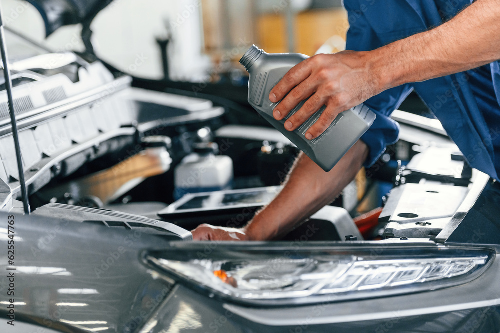 With fuel can. Auto mechanic working in garage. Repair service