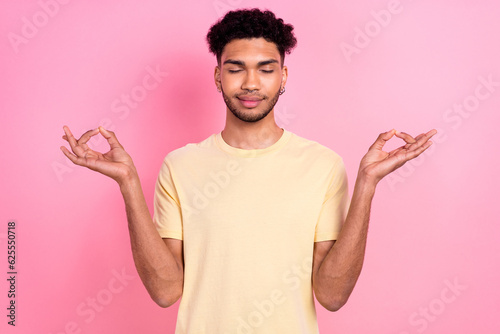 Photo of peaceful positive guy with afro hairstyle dressed yellow t-shirt make meditation exercise isolated on pink color background