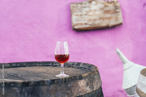 Wallpaper Mural A glass of alcoholic beverage - Portuguese sweet wine Moscatel on a wooden barrel, purple wall, rustic elements Torontodigital.ca