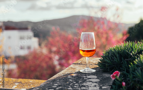 A glass of orange beverage - Moscatel de Setubal on a terrace with trees view, sunset, Portugal photo