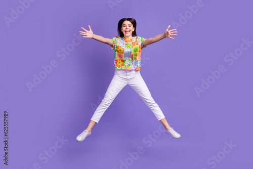 Full length photo of good mood girl dressed flower print t-shirt jumping stretching hands to hug you isolated on violet color background