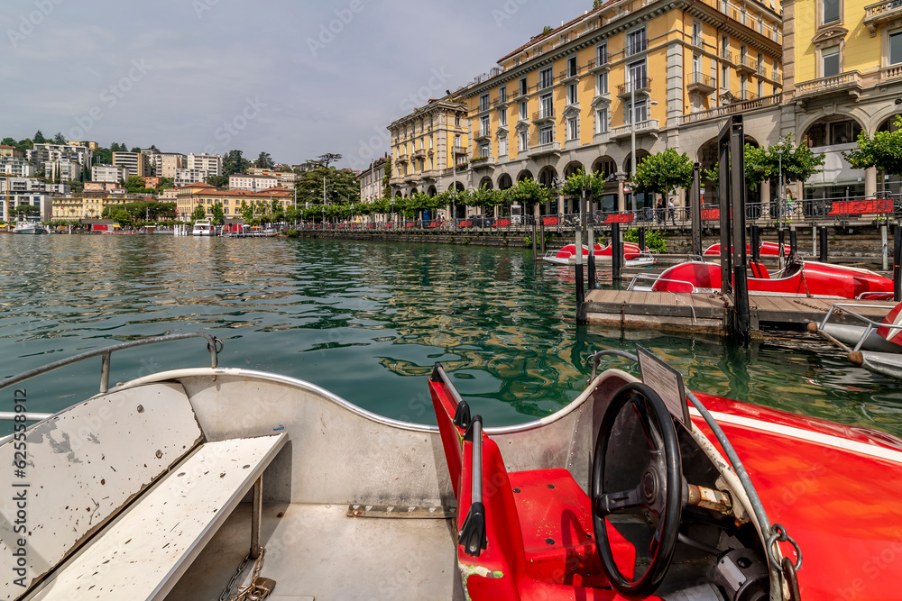 Funny red racing car shaped boats on Lake Lugano, Switzerland, with the city in the background
